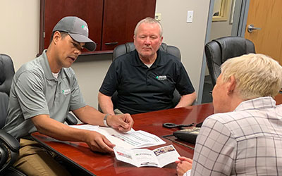Lechner First Aid Sales Representatives discussing a Lechner First Aid brochure at a table with a business owner. 