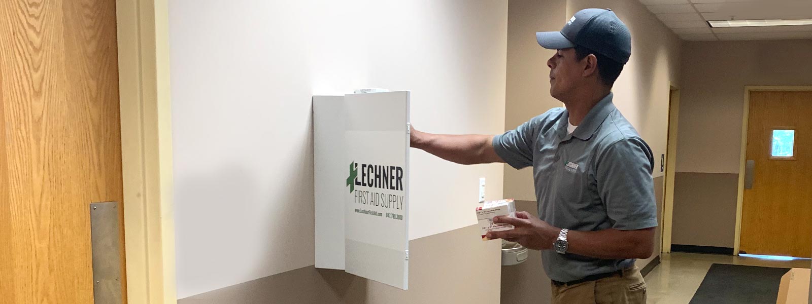 Lechner First Aid Sales Representative putting first aid supplies and ppe in a First Aid cabinet. 