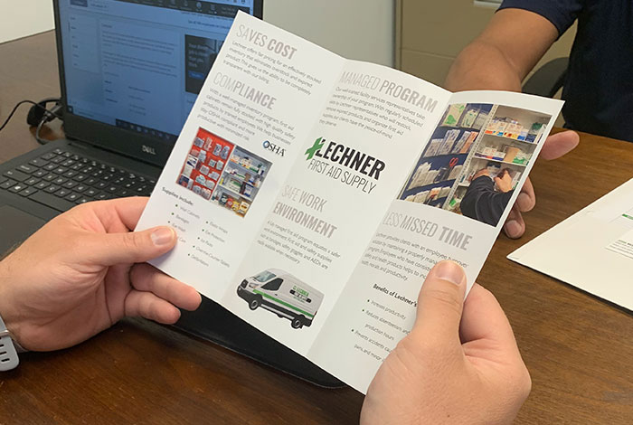 A Lechner First Aid Sales Representative holding a Lechner First Aid Supply Brochure. 