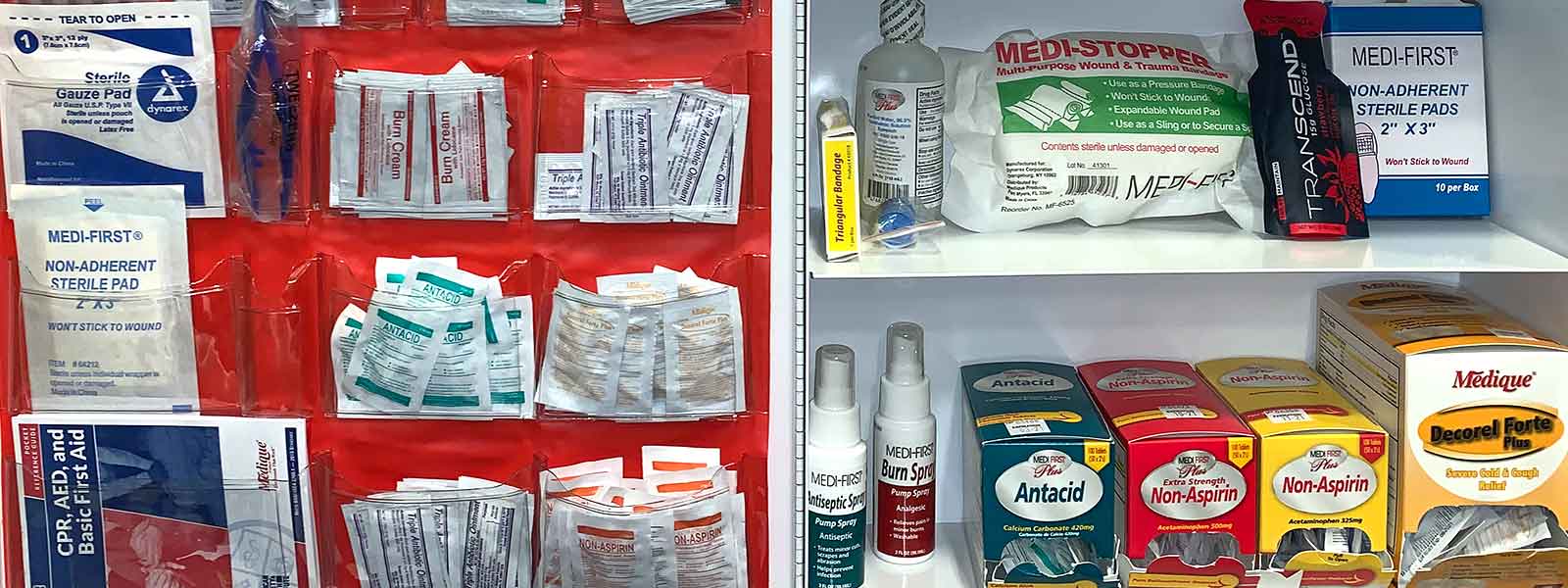 An open Lechner First Aid Supply cabinet with various first aid, personal protective equipment, and safety items inside. 