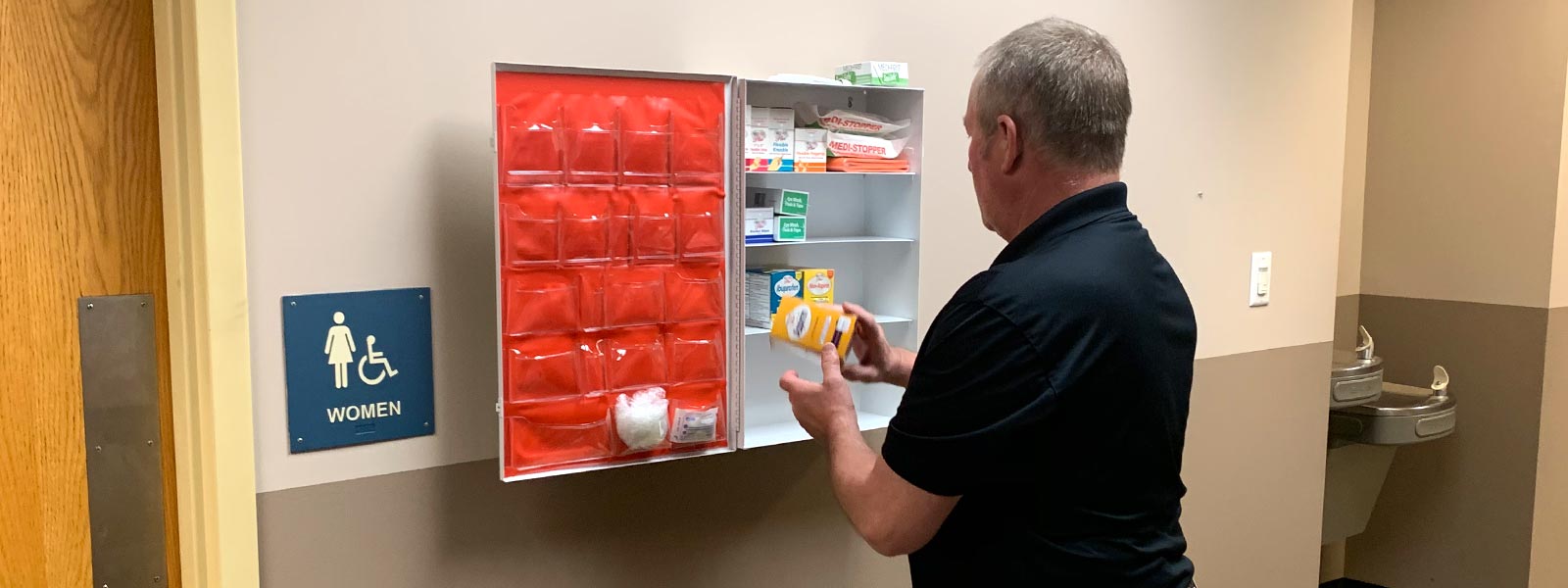 Lechner First Aid employee stocks a First Aid Supply cabinet with first aid supplies, ppe, and other products to keep employees safe. 