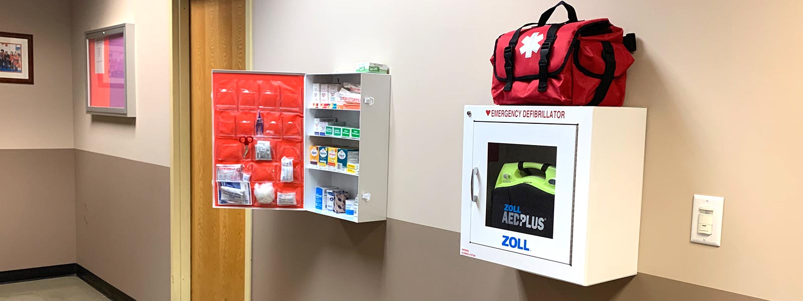 Lechner AED unit and First Aid cabinet hanging in a hallway.