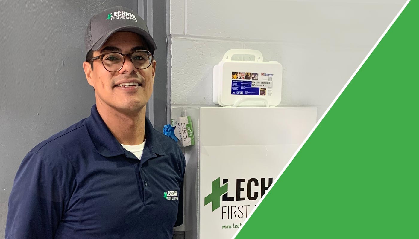 A Lechner First Aid Sales Representative standing by a Lechner First Aid kit/First Aid cabinet. 